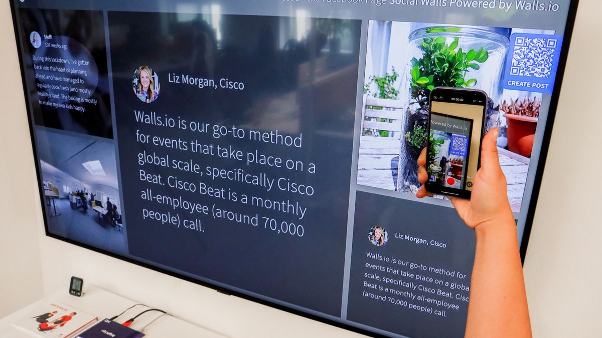 A person scanning a QR code displayed on a large screen